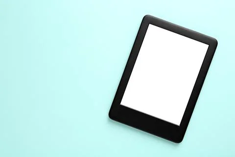 Modern e-book reader with blank screen on light blue background, top view. Sp Stock Photos