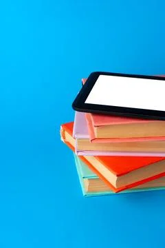 Modern e-book on stack of hardcover books on blue background 写真素材