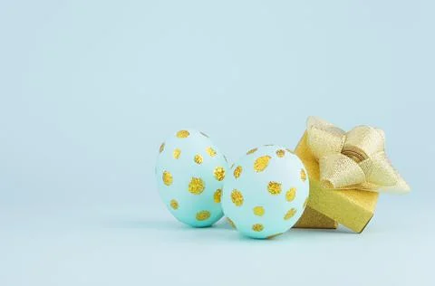 Modern easter eggs with golden dots and opened gift box on blue background, c Stock Photos