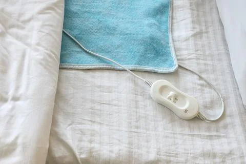 Modern electric heating pad on bed, top view Stock Photos