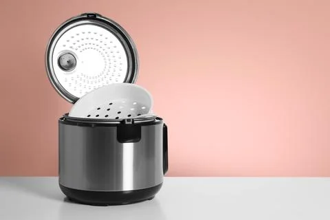 Modern electric multi cooker on table against color background. Space for tex Stock Photos