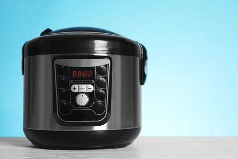 Modern electric multi cooker on table against color background. Space for tex Foto stock
