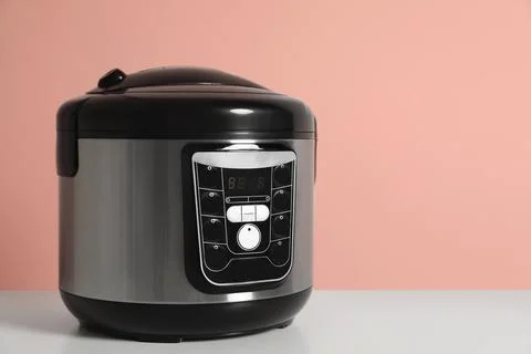 Modern electric multi cooker on table against color background. Space for tex Stock Photos