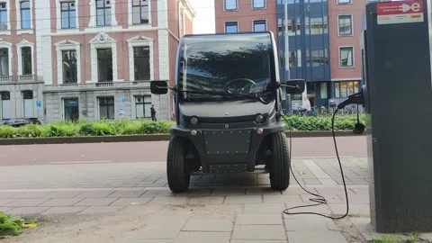 Modern electric two-seat micro car being charged in the street Stock Footage 219953165