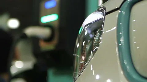 Modern electric vehicle connected to grid through plug at public charging point Stock Footage