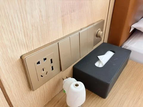 Modern electrical outlet with tissue box and sanitizer on wooden surface. Фото