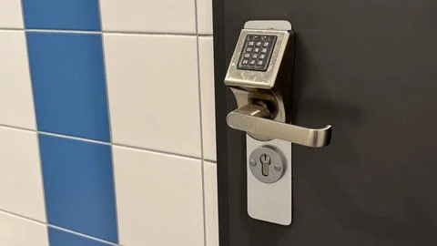 Modern electronic door lock with keypad on a dark door next to blue and whi.. Stock Photos