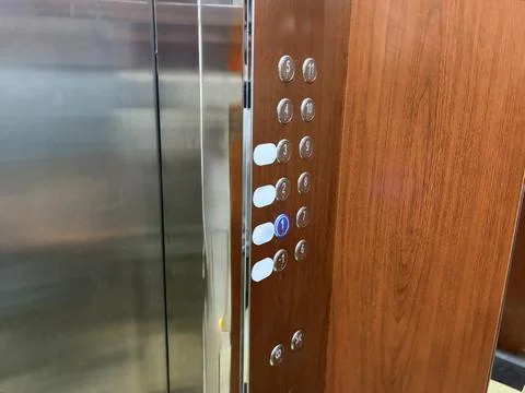 Modern Elevator Interior with Wooden Panel and Illuminated Floor Buttons Stock Photos