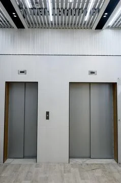 Modern elevator lobby with two metal doors and designer ceiling. Stock Photos