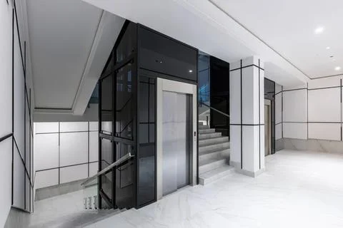 Modern elevator in a sleek building with stairs nearby Stock Photos