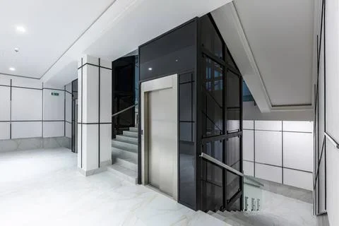 Modern elevator in sleek building with stairs and glass walls Stock Photos