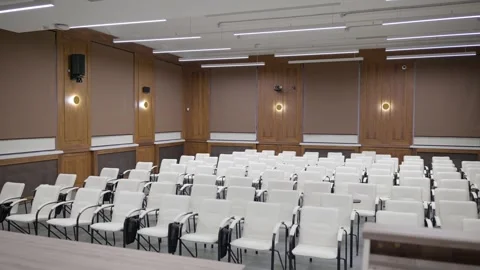 Modern empty classroom, lecture hall, with white chairs and brown walls Stock Footage 302473593
