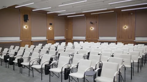 Modern empty classroom, lecture hall, with white chairs and brown walls Stock Footage 302473612