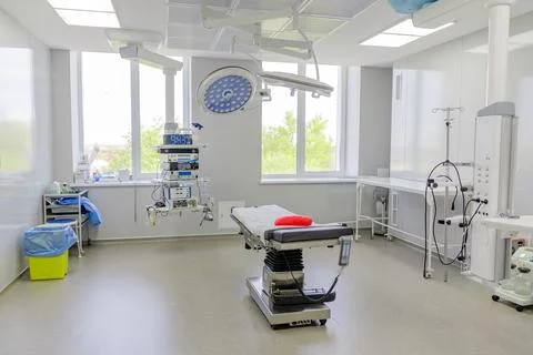 Modern empty operating room with surgical equipment and medical bed Stock Photos