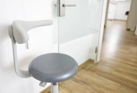A modern, ergonomic stool with a backrest, positioned in a well-lit office .. Stock Photos