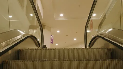 Modern escalator moving upwards inside a bright commercial shopping mall 库存影片 343420109