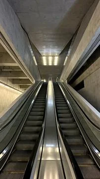 Modern escalators ascend between raw concrete walls in a minimalist archite.. Stock Photos