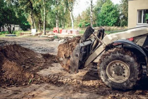 The modern excavator performs excavation work on the construction site. View on Stock Photos