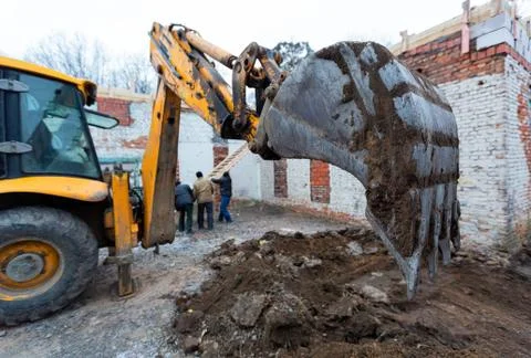 The modern excavator performs excavation work on the construction site. Front Stock Photos
