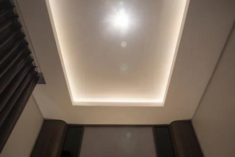 Modern false ceiling with recessed LED strip lighting, central spotlight, a.. Stock Photos