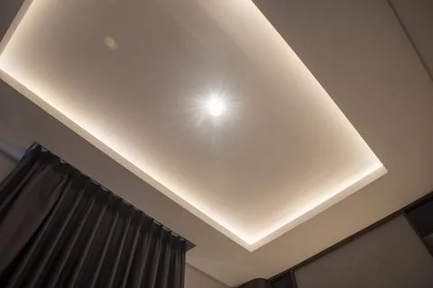 Modern false ceiling with recessed LED strip lighting, a central spotlight,.. Stock Photos