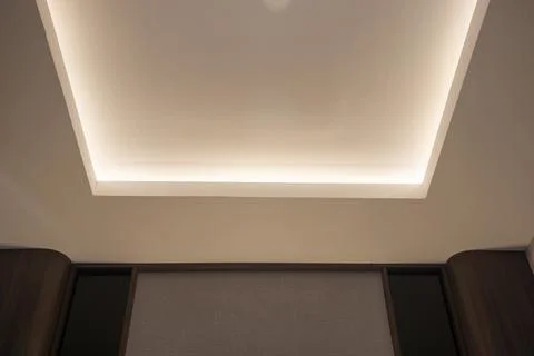 Modern false ceiling with recessed LED strip lighting above a paneled headb.. Stock Photos