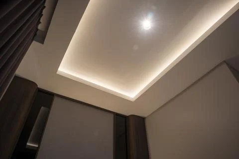 Modern false ceiling with recessed LED strip lighting, central spotlight, a.. Stock Photos