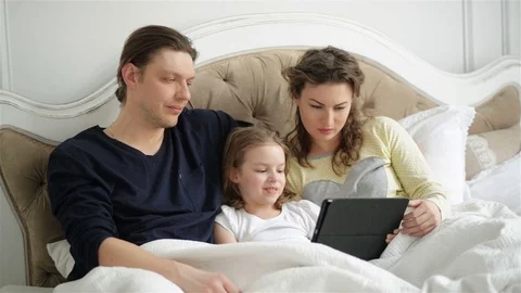 Modern Family is Using Electronic Gadget Lying on the Bed Together. Handsome Man Stock Footage 73751942
