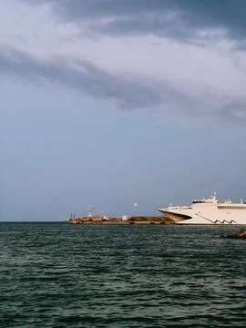 Modern ferry docking at pier on cloudy day, surrounded by calm sea and featuring Foto stock