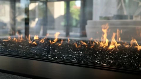 Modern fireplace with flames burning over bed of decorative stones or glass Stock Footage 276374269