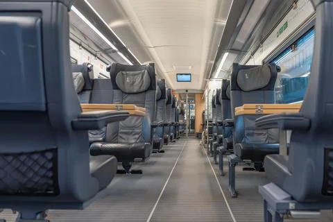 Modern first-class train carriage with spacious leather seats and foldable Stock Photos