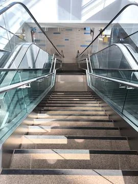 A modern fixed staircase between two escalators at an airport 스톡 사진