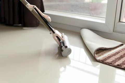 Modern Floor Mop Cleaning Underneath Rolled Up Area Rug Stock Photos