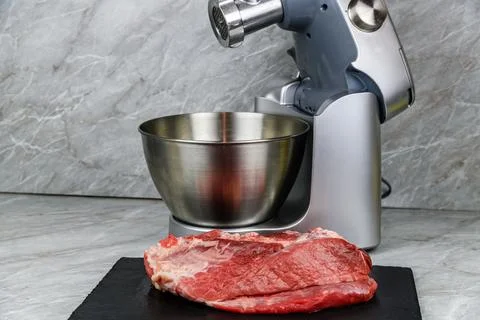 Modern food processor with meat grinder and peace of pork meat at kitchen Stock Photos