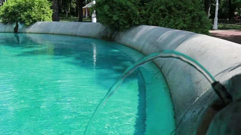 Modern Fountain with Arching Water Stream into Turquoise Pool Stock Footage 334884772