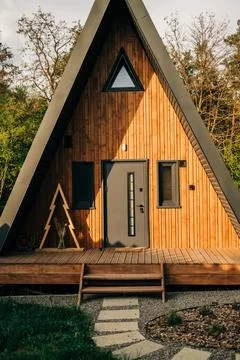 Modern A-frame house exterior, triangular cabin surrounded by nature Stock Photos