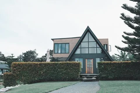 Modern A-Frame House with Large Windows Surrounded by Neatly Trimmed Hedges.. Stock Photos