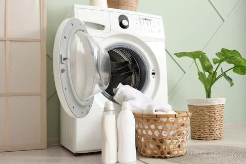 Modern front-load washing machine with open door, laundry basket, detergent b Stock Photos