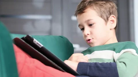 Modern generation. Kid playing on ipad. Little boy is smiling while playing with Stock Footage 160974568
