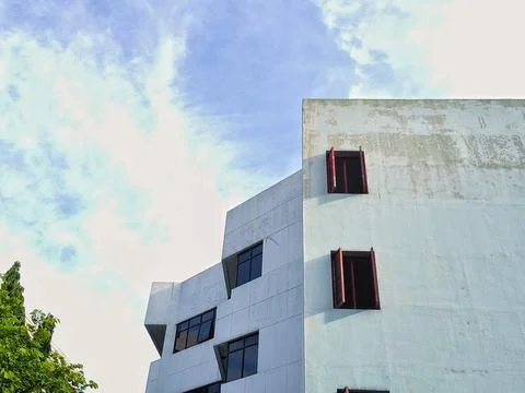 Modern geometric building facade with red windows under blue sky Stock Photos