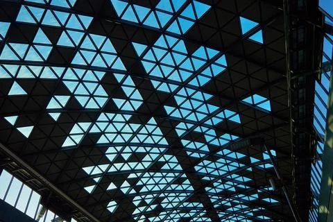 Modern glass ceiling with triangular pattern against blue sky. 스톡 사진