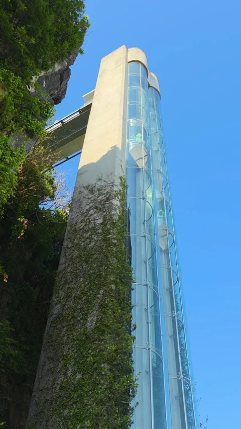 Modern glass elevator ascending steep ivy covered cliff at Marble Mountains Da Stock Footage 332802306
