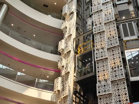 Modern glass elevator with decorative geometric pattern shaft inside a mall Stock Photos