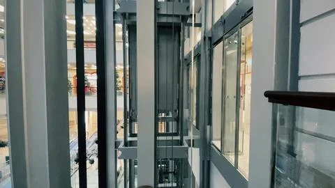 Modern glass elevator shaft inside shopping mall Stock Photos