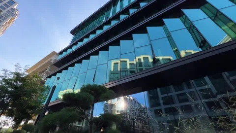 Modern Glass Office Building with Angular Facade Design Low Angle Wide Shot Vídeos de archivo 312361794