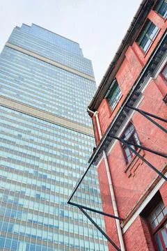 Modern glass skyscraper contrasts historic brick building urban architecture Stock Photos