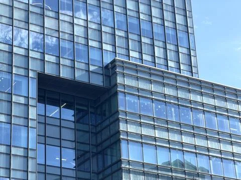 Modern glass skyscraper facade reflecting blue sky and clouds on a sunny day Stock Photos