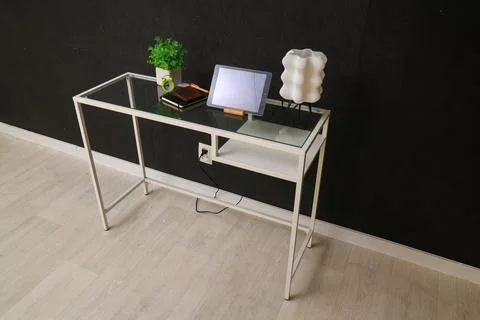 Modern glass-top console table with decorative lamp and tablet Stock Photos