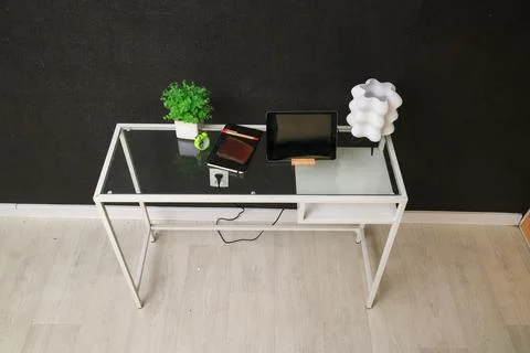 Modern glass-top desk setup with tablet, plant, and unique lamp Stock Photos