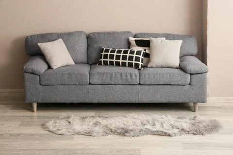 Modern gray fabric sofa with decorative pillows and a faux fur rug in a minim Stock Photos